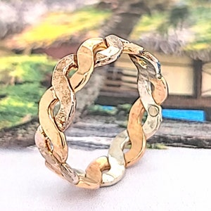 May include: A gold and silver braided ring with a textured finish.