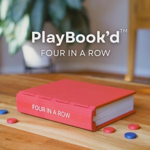 Może przedstawiać: Czerwona gra PlayBook'd Four in a Row na drewnianym stole. Gra jest w etui przypominającym książkę z białym tekstem. Rozrzucone są czerwone i niebieskie elementy gry.