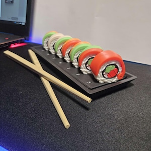 Sushi relleno - Pastillero semanal y llaveros - Incluye bolígrafos con palillos y bloc de notas.