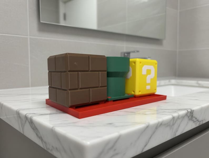 May include: A red tray holds a brown brick block, a green pipe, and a yellow question mark block. The items are arranged on a white marble countertop in a bathroom setting. The objects are reminiscent of a popular video game.