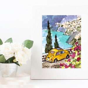 May include: Watercolor painting of a yellow Fiat car driving along a winding road overlooking a blue ocean and a small town on a cliffside. The painting is framed in a white frame and has the text "Italy" written at the bottom.