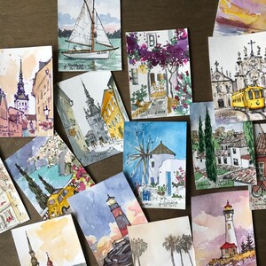 May include: A collection of 14 watercolor paintings on paper, each depicting a different city or town. The paintings are all in a similar style, with a focus on architecture and urban landscapes. Some of the paintings include text, such as "Tallinn,  Estonia" and "Porto".