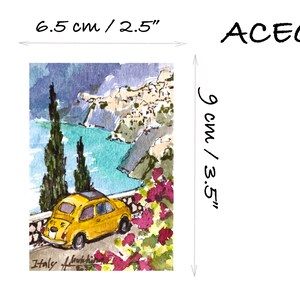 May include: A watercolor painting of a yellow Fiat car driving along a winding road overlooking a blue ocean and a white village. The painting is 9 inches by 6.5 inches and is signed "Italy" in the bottom left corner.