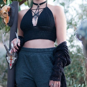 Peut inclure: Un haut de bikini noir en crochet avec un motif d'&eacute;toile et un collier ras du cou noir. Le haut est port&eacute; avec un pantalon de surv&ecirc;tement gris fonc&eacute; et un cardigan noir en crochet.