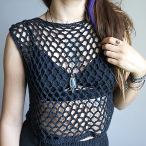 May include: A black crochet top with a loose, open weave. The top is sleeveless and has a scoop neck. A silver necklace with a dark blue stone pendant is worn over the top.