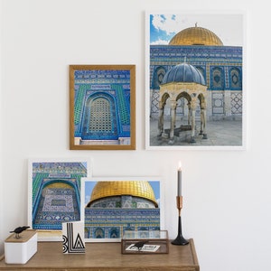Puede incluir: Cuatro impresiones enmarcadas de la Cúpula de la Roca en Jerusalén, una mezquita con una cúpula dorada y intrincados azulejos azules y verdes. Las impresiones se muestran en una cómoda de madera con un candelero negro y un pequeño objeto decorativo en blanco y negro.