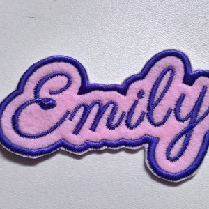 May include: Pink felt patch with the name "Emily" embroidered in purple thread.