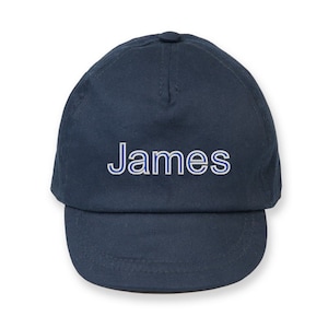 May include: A navy blue baseball cap with the name "James" embroidered in white with a blue outline.