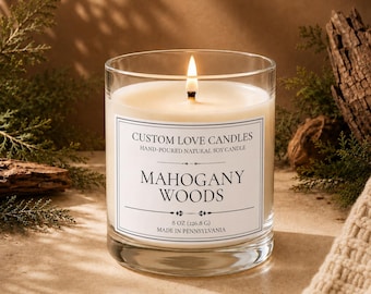 May include: A clear glass jar candle with a lit wick and white wax. The label reads: CUSTOM LOVE CANDLES, HAND-POURED NATURAL SOY CANDLE, MAHOGANY WOODS, 8 OZ (226.8 G), MADE IN PENNSYLVANIA. The candle features a simple, clean design.