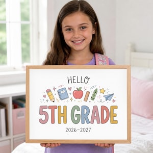 Peut inclure: Un cadre en bois rectangulaire contenant une affiche blanche avec le texte HELLO 5TH GRADE 2026-2027. Le design présente des illustrations colorées d'un crayon, d'un cahier, d'une pomme, d'une règle, d'un crayon de cire, d'une étoile et d'un avion en papier.