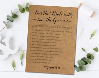 以下が含まれることがあります： 「Does the Bride really know the Groom?」のテキストと一連の質問が書かれたクラフト紙のブライダルシャワーゲームカード。カードにはゲストの推測のためのスペースが含まれています。背景にはユーカリとリボンがあります。