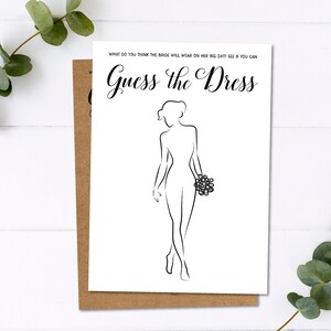 Pu&ograve; includere: Una carta bianca con la scritta "Guess the Dress" e un disegno a tratto di una sposa che tiene un bouquet. La carta &egrave; sopra una carta marrone, con foglie di eucalipto sullo sfondo.