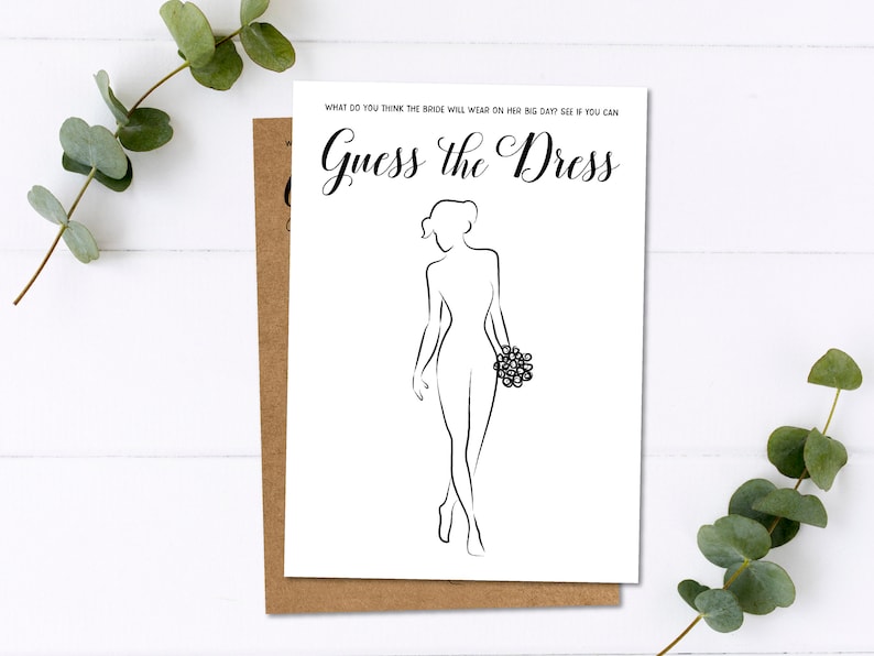 Pu&ograve; includere: Una carta bianca con la scritta "Guess the Dress" e un disegno a tratto di una sposa che tiene un bouquet. La carta &egrave; sopra una carta marrone, con foglie di eucalipto sullo sfondo.