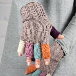 Può includere: Un paio di guanti senza dita con una base di colore marrone e accenti colorati sulla punta delle dita. Le punte delle dita sono di colore crema, rosa, azzurro e arancione.