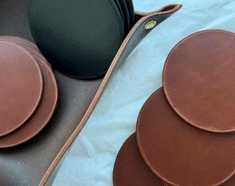 May include: A set of brown leather coasters and a set of black leather coasters in a brown leather tray.
