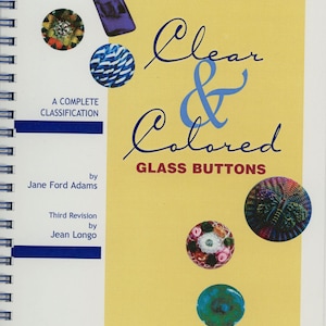 May include: A book cover titled "Clear & Colored Glass Buttons" with various colorful glass button examples. The cover is yellow with blue accents and includes the text "A Complete Classification" and author names.