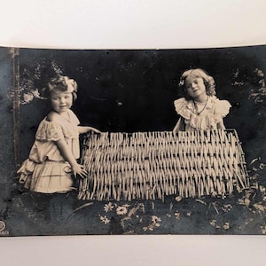 Cartão postal com foto real de duas meninas em vestidos brancos com cerca de vime, RPPC do início dos anos 1900, escrita dinamarquesa, cartão postal com foto vintage