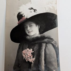 Antica cartolina postale RPPC del 1909 con foto autentica, donna in pelliccia e cappello con piuma, ritratto di moda colorato a mano, timbro postale norvegese