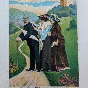 Antike Postkarte 1910s – Zwei Frauen benutzen den Rücken eines Mannes als Kartenschreibtisch – Humorvolle Vintage-Reiseszene