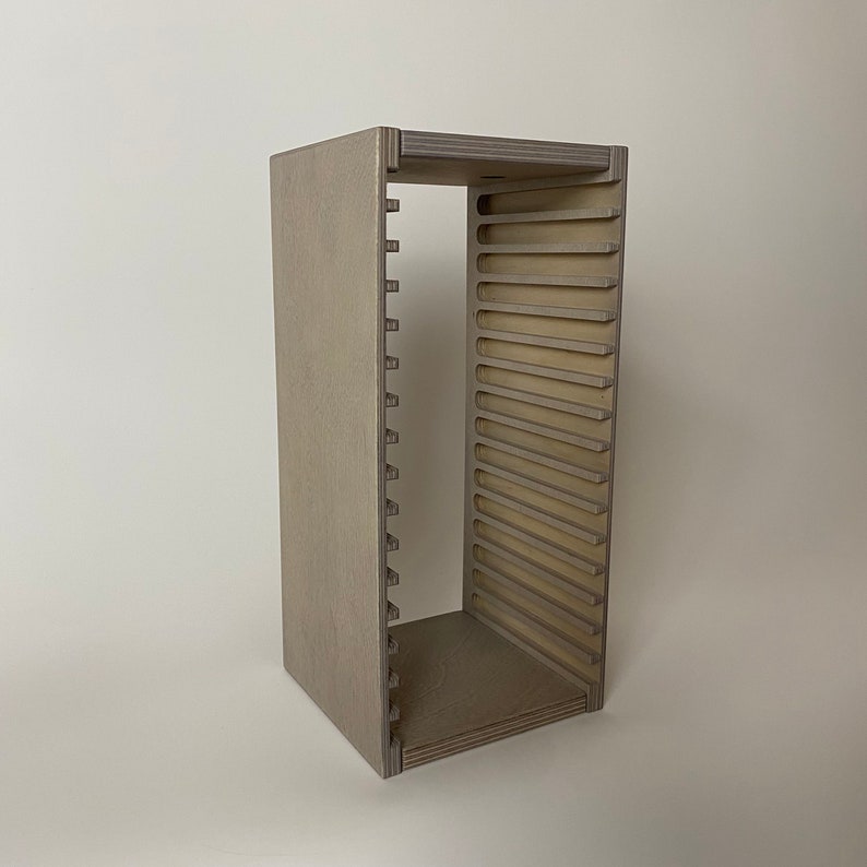 Peut inclure: Un rack de rangement en bois gris pour CD avec des fentes pour ranger les CD. Le rack est en contreplaqu&eacute; et a un design simple et moderne.