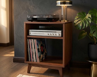 Puede incluir: Un soporte de madera para tocadiscos con cuatro patas cónicas, que cuenta con un estante superior abierto con un tocadiscos negro, un estante central con un receptor de audio plateado y un estante inferior con una colección de discos de vinilo.