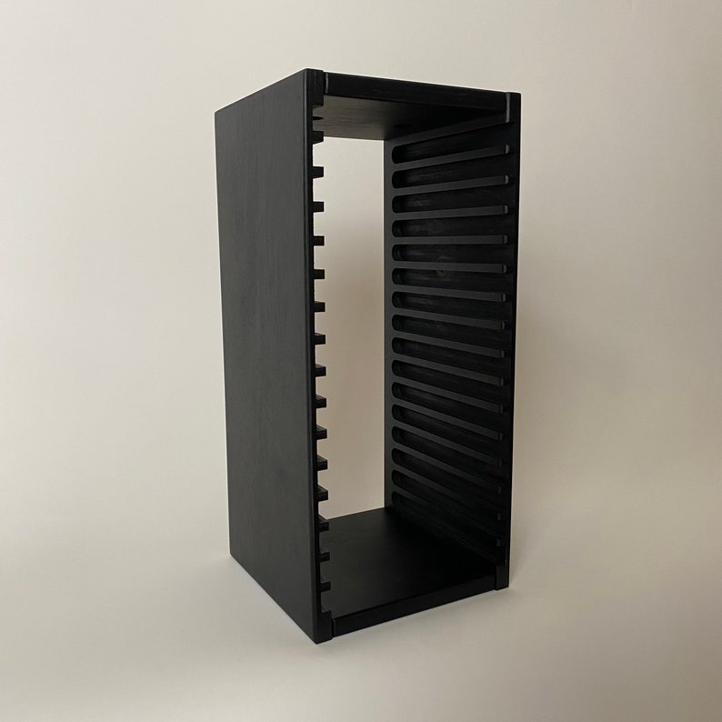 Peut inclure: Un rack de rangement en bois noir pour CD avec plusieurs fentes pour ranger les CD. Le rack est en bois et a un design &eacute;l&eacute;gant et moderne.