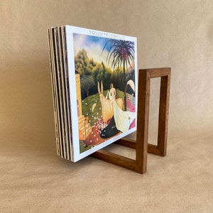 May include: A wooden record stand holding a stack of vinyl records. The record cover shows a painting of a woman riding a white donkey in a woodland scene. The album title is "Through the Looking Glass" by "Mike Oldfield".