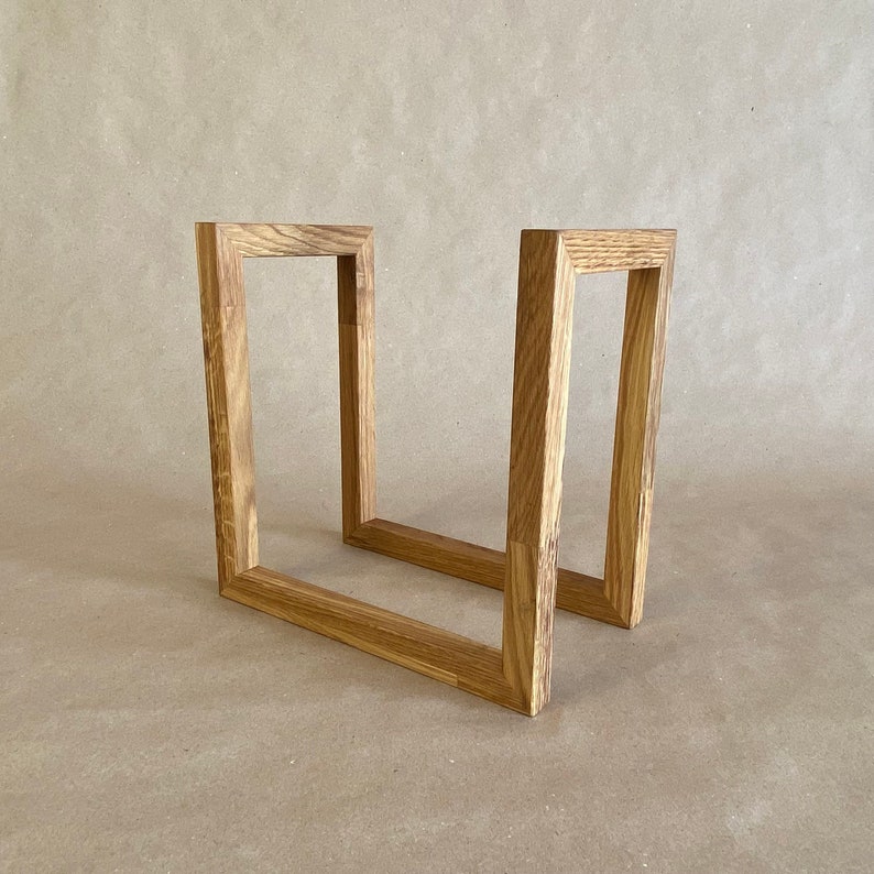 May include: A wooden frame made of two rectangular pieces of wood joined together to form a U-shape.