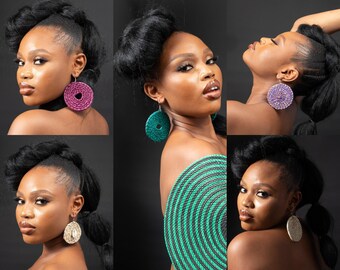 May include: A collection of circular woven earrings in various colors including magenta, green, purple, and beige. Some earrings feature a central cowrie shell accent. The designs are round, textured, and suspended from silver-toned metal earring hooks.