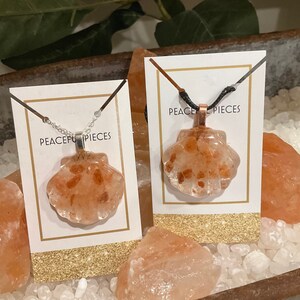 May include: Two necklaces with pink Himalayan salt shell pendants. The necklaces are on white cards with the text "Peaceful Pieces".