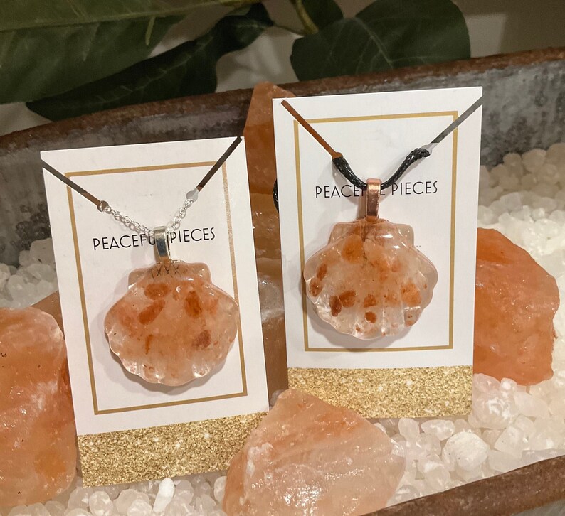 May include: Two necklaces with pink Himalayan salt shell pendants. The necklaces are on white cards with the text "Peaceful Pieces".