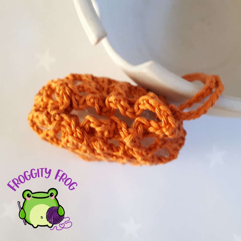 Orange cotton soap saver shown from above with the drawstring pulled tight to secure the bar of soap