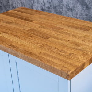 May include: A light blue cabinet with a natural wood countertop. The countertop is made of multiple pieces of wood that are joined together.