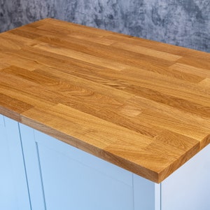May include: A light blue cabinet with a wood worktop. The worktop is made of natural wood planks.