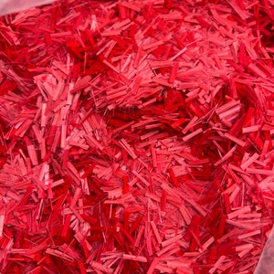 May include: A close-up of a bag filled with red fiberglass strands. The strands are long and thin, and they are all tangled together.