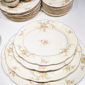 May include: A set of vintage floral china dinnerware with a delicate pink and white floral pattern. The set includes plates, bowls, and cups.