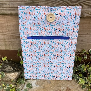 May include: A white zippered pouch with a blue zipper and a brown button that says "Handmade with Love". The pouch has a white background with a pattern of colourful leaves.