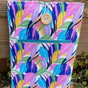 May include: A colorful fabric pouch with a zipper closure and a wooden button that says "Handmade with Love". The pouch has a white background with a pattern of blue, pink, yellow, and green leaves.