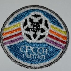 May include: A blue and white embroidered patch with the text "EPCOT CENTER" and a stylized globe with rainbow stripes.