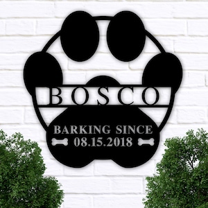 May include: Black metal paw print sign with the name "BOSCO" and the text "Barking Since 08.15.2018" with bone icons on either side.
