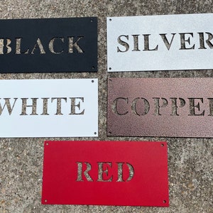 May include: Five metal signs with different colours and the words "BLACK", "SILVER", "WHITE", "COPPER", and "RED" cut out of the metal.