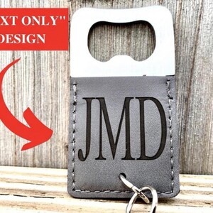 May include: A silver bottle opener with a gray leatherette sleeve. The sleeve is engraved with the initials "JMD" and includes a key ring. The text "TEXT ONLY" DESIGN is in a red rectangle.