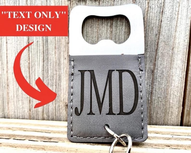 May include: A silver bottle opener with a gray leatherette sleeve. The sleeve is engraved with the initials "JMD" and includes a key ring. The text "TEXT ONLY" DESIGN is in a red rectangle.