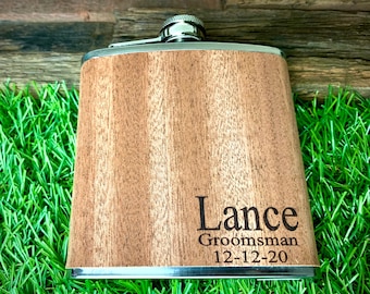 May include: A wooden flask with a silver top and a personalized inscription that reads "Lance  Groomsman 12-12-20".