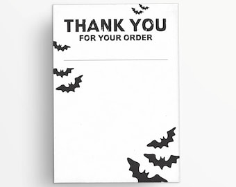 May include: A white card with the text "THANK YOU FOR YOUR ORDER" in bold black letters. Black bat silhouettes are scattered around the card, which has a blank space for a message. The card is likely for a Halloween-themed order.