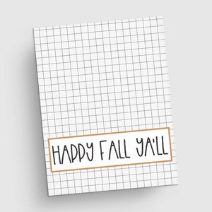 May include: A white notepad with a grid pattern and the text "HAPPY FALL Y'ALL" in a brown rectangular frame. The text is in a handwritten style, perfect for autumn-themed notes or lists.