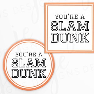 May include: Two round orange and white coasters with the text "You're a Slam Dunk" in black.