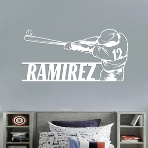 Pu&ograve; includere: Silhouette bianca di un giocatore di baseball che swinga una mazza con il nome "RAMIREZ" e il numero "12" sulla maglia.