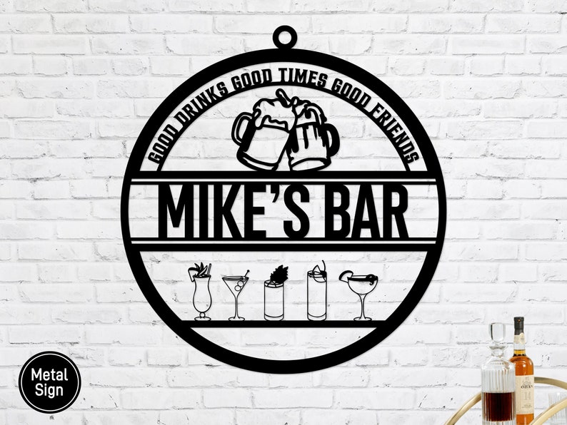 Pu&ograve; includere: Un cartello in metallo nero di forma rotonda con il testo "Good Drinks Good Times Good Friends Mike's Bar" con una grafica di due boccali di birra che brindano e una fila di sei diverse icone di bevande.