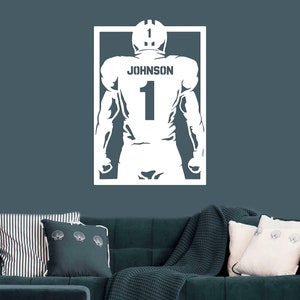Pu&ograve; includere: Silhouette bianca di un giocatore di football americano che indossa una maglia con il nome "JOHNSON" e il numero "1" sul retro. La silhouette &egrave; all'interno di un rettangolo bianco.